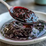 A deep purple Black Currant Reduction drizzled over seared duck breast on a white plate.