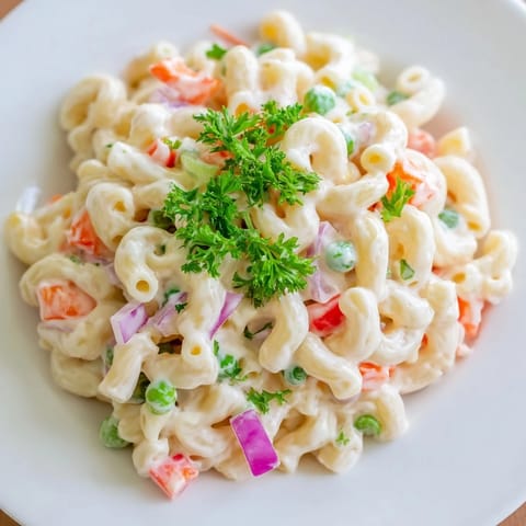 A close-up of a vibrantly dressed macaroni salad, perfect for a picnic side dish.