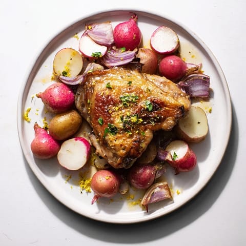 A close-up of the Roasted Radish & Chicken Sheet Pan dinner, with golden chicken skin and tender vegetables glistening with olive oil.  