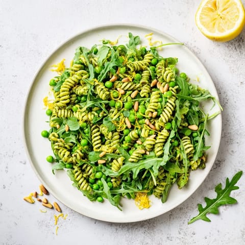 Overhead view of Spring Green Pesto Pasta Salad, vibrant greens, and crumbled feta in a serving bowl.