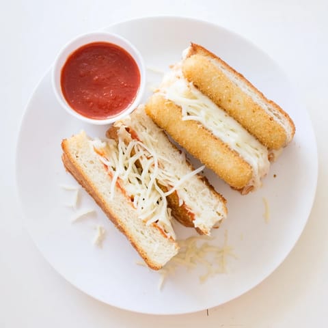 Perfectly golden grilled cheese sandwich stuffed with mozzarella sticks, oozing melted cheese served with a side of warm marinara for dipping.