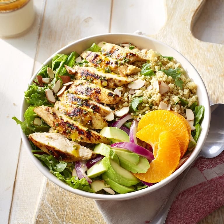 Bright quinoa salad with herb-marinated grilled chicken, fresh orange slices, creamy avocado, and a zesty citrus vinaigrette on mixed greens.