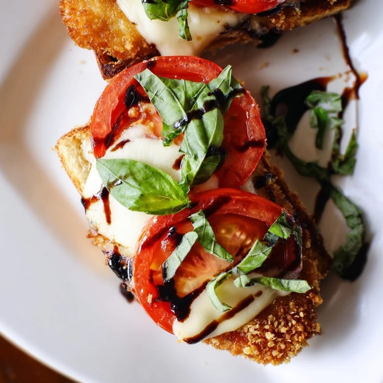 A close-up of a toasted ciabatta sandwich filled with golden fried chicken, fresh basil leaves, and melted mozzarella.