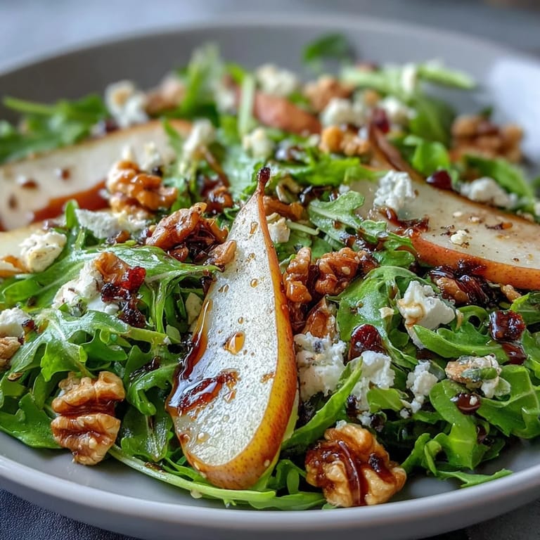 Arugula and Pear Bowl salad with glistening balsamic vinaigrette, juicy pear wedges, blue cheese crumbles, and chopped pecans, ready to serve as a light main course.