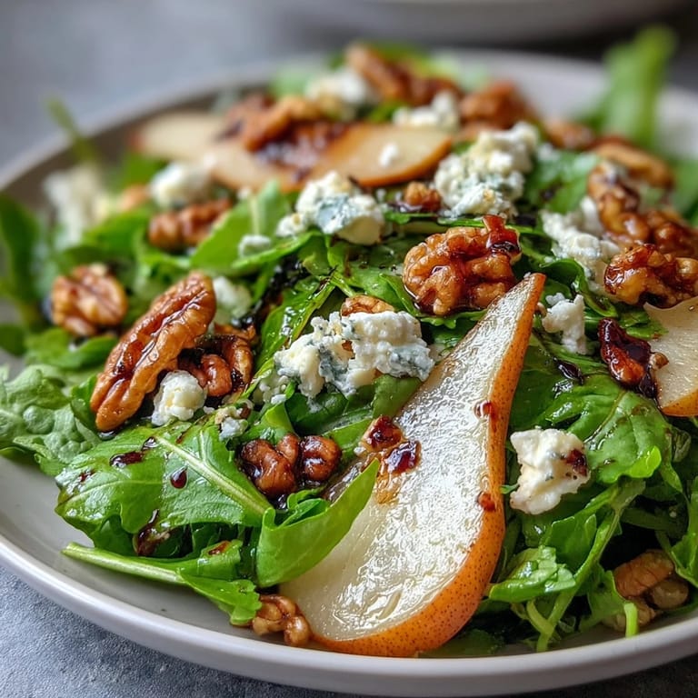 Vibrant Arugula and Pear Bowl with bright green arugula, thin pear slices, goat cheese, and walnuts, garnished with a drizzle of honey-balsamic dressing for a refreshing starter.