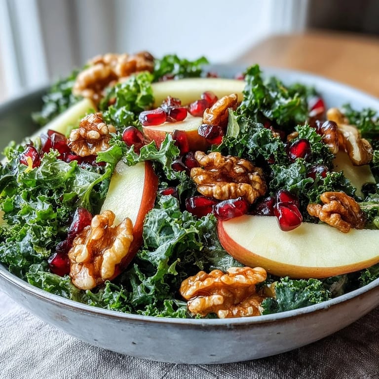 A close-up of the Kale and Pomegranate Bowl drizzled with honey-Dijon dressing, highlighting the ruby seeds, green leaves, and toasted nuts for a healthy salad.
