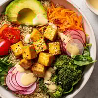 A colorful Buddha Bowl filled with quinoa, roasted tofu, and a creamy tahini dressing, delicious!