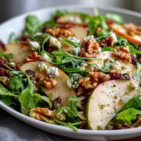 A vibrant Apple and Walnut Salad features crisp apple slices, crunchy toasted walnuts, and mixed greens tossed in a tangy vinaigrette.