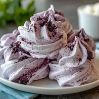 Elegant black currant meringues with a crisp shell and soft, airy center, swirled with tangy berry powder.